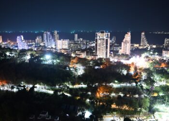 Elevated night view of the Pattaya, Thailand skyline, showing residential and commercial towers along the coast