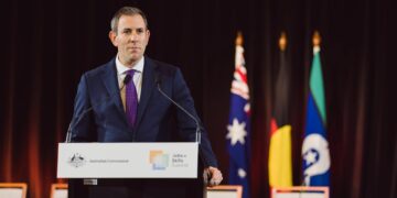 Australian Treasurer Jim Chalmers speaking at a lectern with Australian Government signage