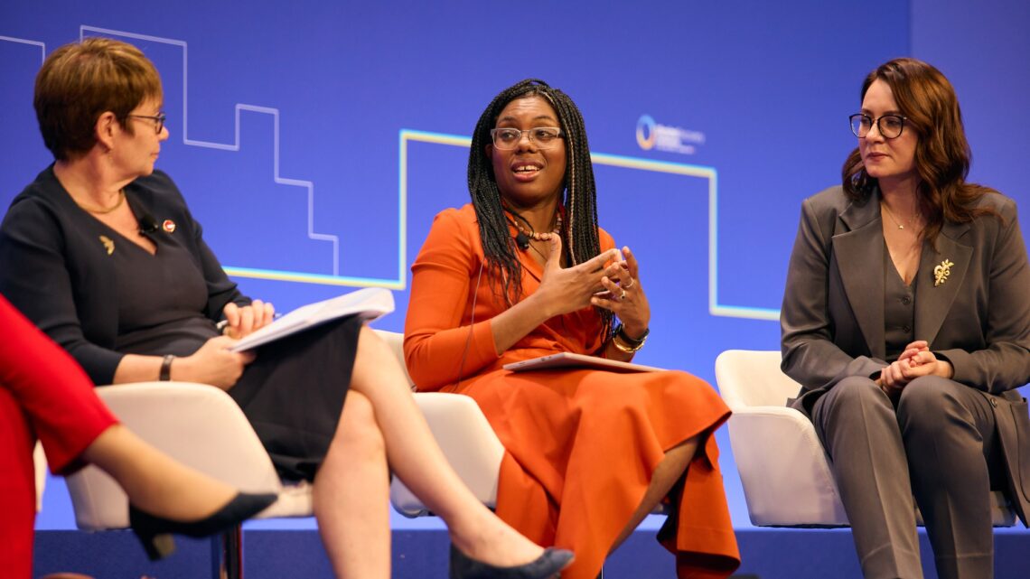 Kemi Badenoch speaking on a panel, flanked by two other women