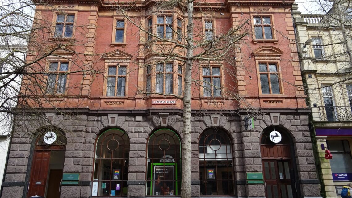 Red-brick facade of a Lloyds Bank branch in Gloucester, UK, with the LLOYDS BANK signage clearly visible