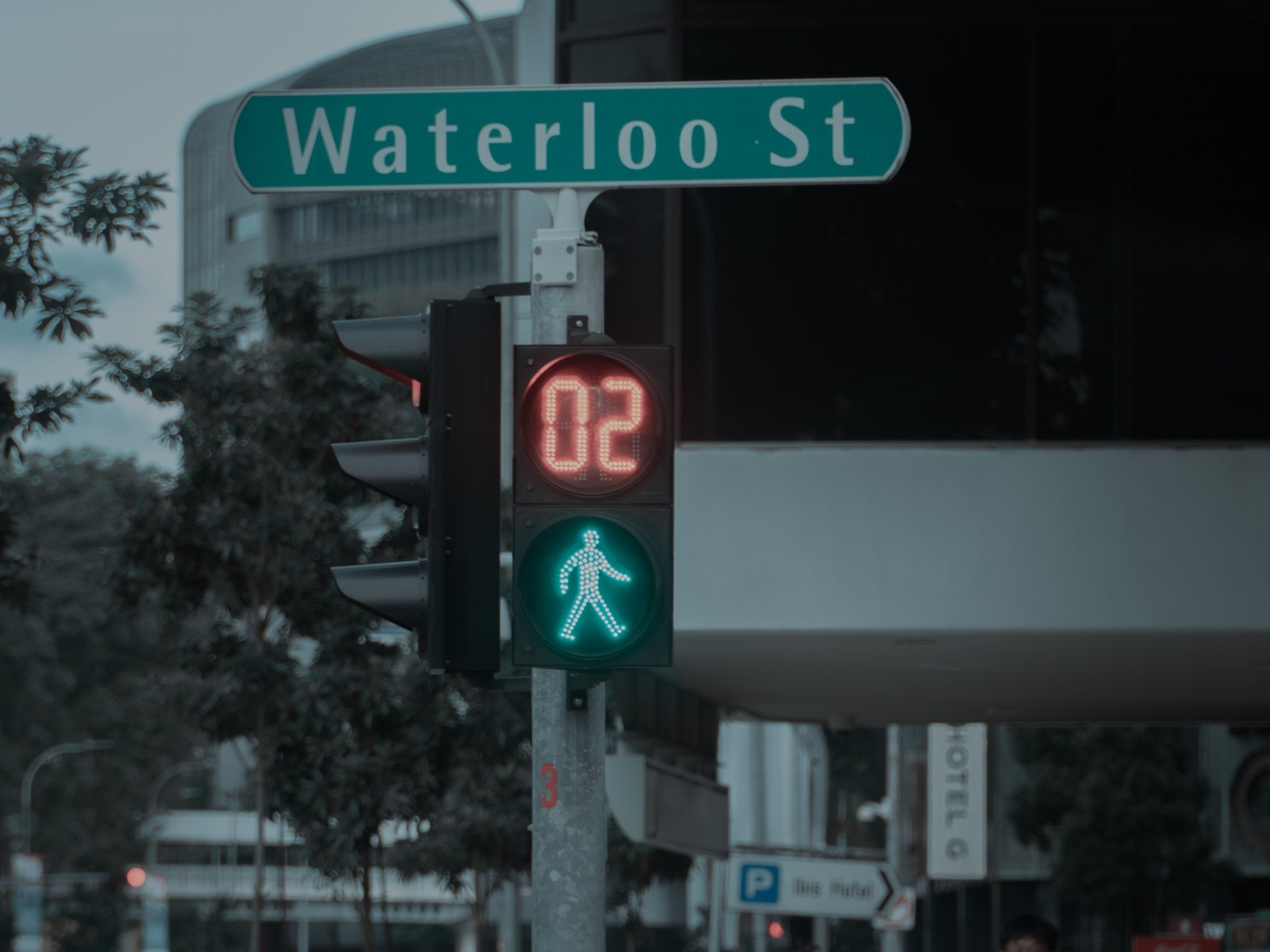 A pedestrian signal at a Waterloo Street junction in Singapore, with the green man lit and a countdown timer