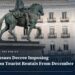 Equestrian statue of Carlos III in Madrid Puerta del Sol, its base spray-painted TOURIST GO HOME, with a housing-protest tent camp behind it