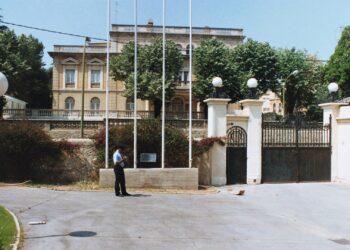 A formal consulate building with gates, flagpoles, and a uniformed guard