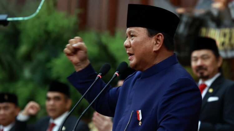 President Prabowo Subianto speaking at a podium with a raised fist
