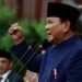 President Prabowo Subianto speaking at a podium with a raised fist