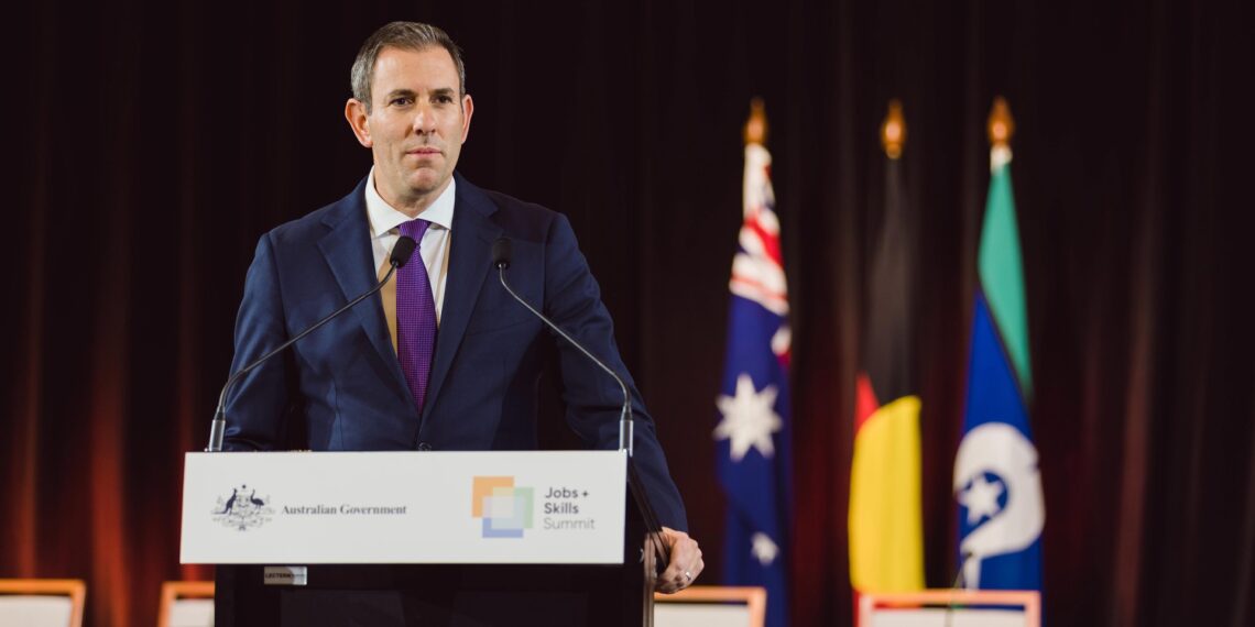 Australian Treasurer Jim Chalmers speaking at a lectern with Australian Government signage