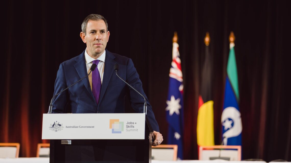Australian Treasurer Jim Chalmers speaking at a lectern with Australian Government signage