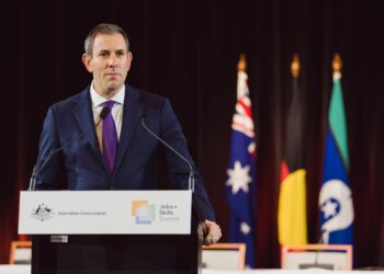 Australian Treasurer Jim Chalmers speaking at a lectern with Australian Government signage