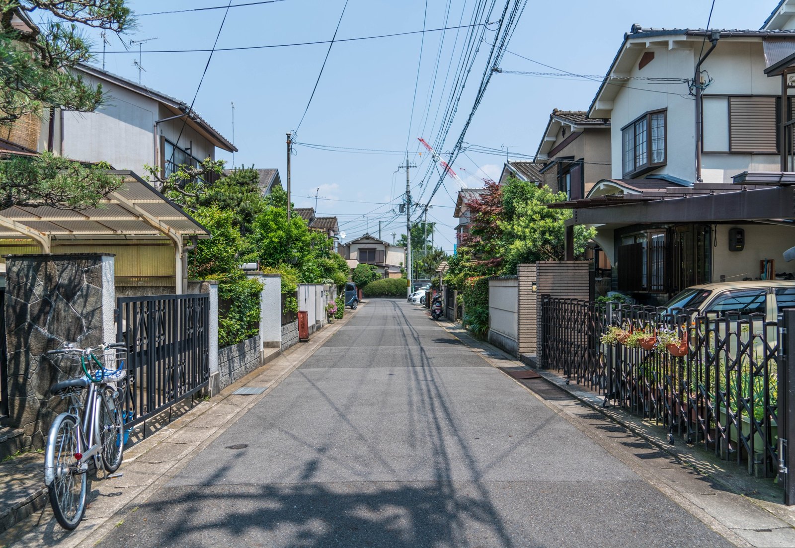 日本住宅區的街道,兩側是獨棟住宅、圍籬與停放的腳踏車