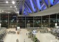 Interior of Suvarnabhumi International Airport's main terminal hall in Bangkok, with check-in counters and travelers