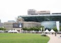 Seoul City Hall's distinctive glass-wave facade rising behind the old stone city hall building, with Seoul Plaza in front